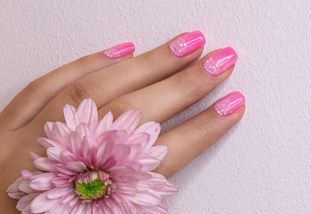 Inspiração de unha tradicional em rosa vivo ao lado de uma flor